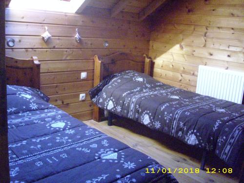Les RibesにあるLe Pin Cembroのログキャビン内のベッドルーム1室(ベッド2台付)