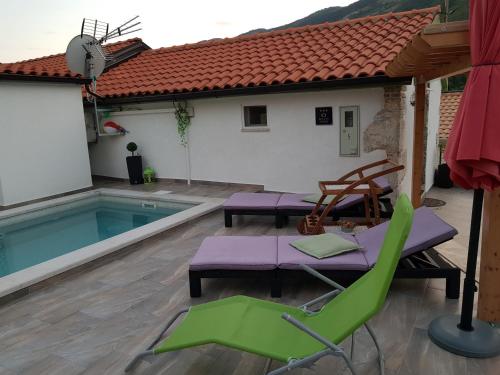 eine Terrasse mit Stühlen, einem Pool und einem Haus in der Unterkunft Diana Holiday Home in Brseč