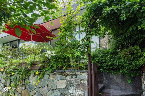 a red umbrella sitting on top of a stone wall at FLAMINGOS Villa Happy BT in Ngọc Quang