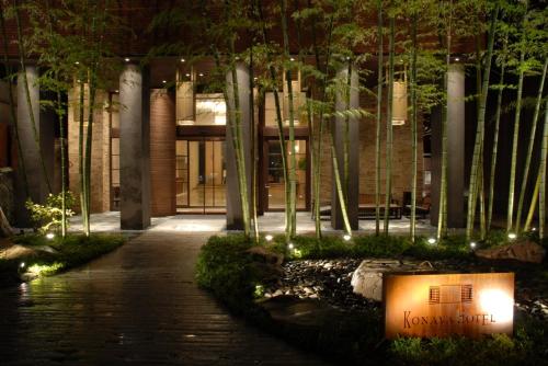 a building with a walkway in front of a building with trees at Konaya Hotel in Kofu