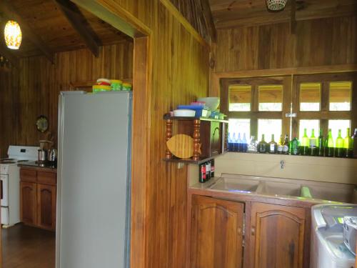 a kitchen with wooden cabinets and a white refrigerator at Cabaña rodeada de naturaleza en San Carlos in Quesada