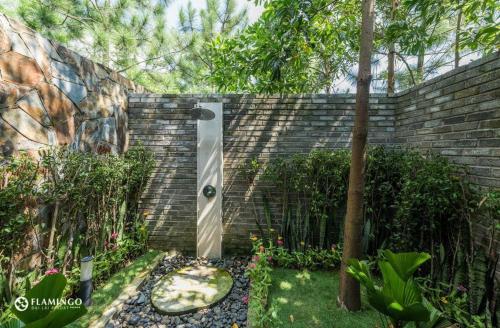 a backyard with a brick wall and a garden at FLAMINGOS Villa Happy BT in Ngọc Quang