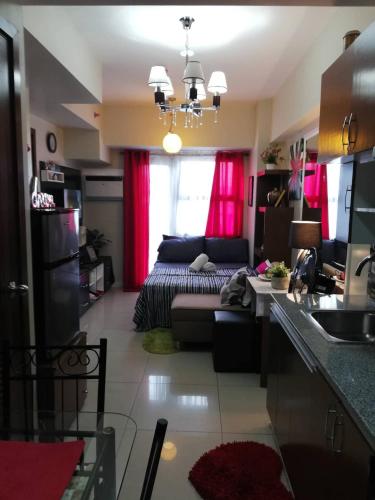 a living room with a couch and red curtains at Nica's Place Property Management Services at Horizons 101 Condominium in Cebu City