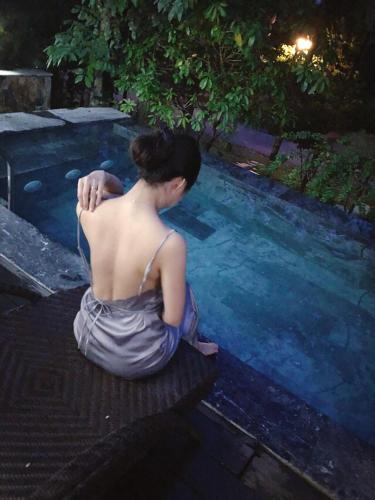 a woman sitting in front of a swimming pool at FLAMINGOS Villa Happy 3 phòng ngủ- view Hồ- bể bơi riêng in Ngọc Quang