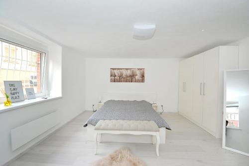 a white bedroom with a bed in a white room at Pure Apartman Pécs in Pécs