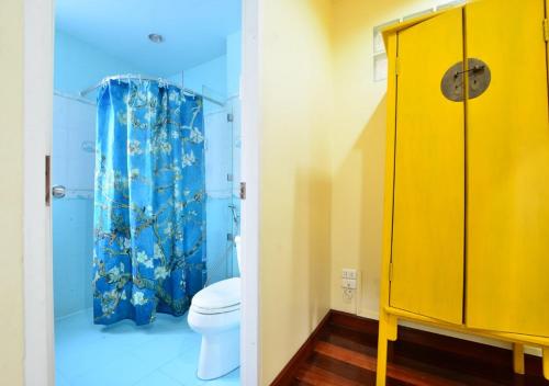 La salle de bains est pourvue de toilettes et d'un rideau de douche jaune. dans l'établissement Ayi Home, à Bangkok