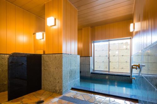 baño con piscina y ventana en Japanese Style Hotel Isomura en Kesennuma