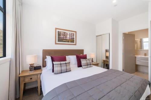 a bedroom with a large white bed with red pillows at Executive 2 Bedroom Apartment Remarkables Park in Queenstown