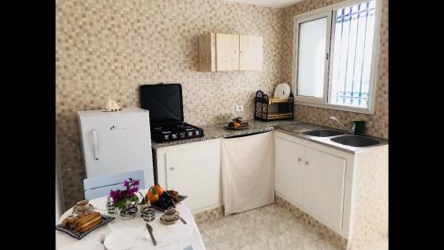 uma cozinha com um frigorífico branco e um lavatório em Dwiret Hayet Kélibia em Kelibia