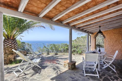 a patio with chairs and a table and the ocean at Rosa dei Venti in Capoliveri