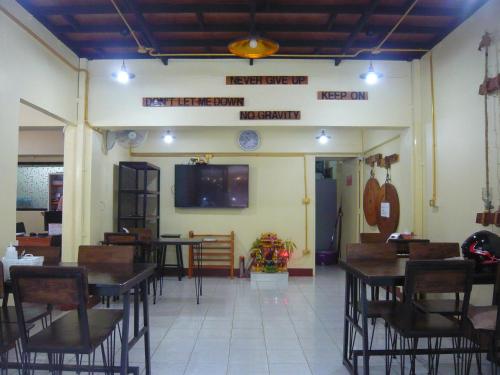a restaurant with tables and chairs and a tv on the wall at 168 Chiangmai Guesthouse in Chiang Mai
