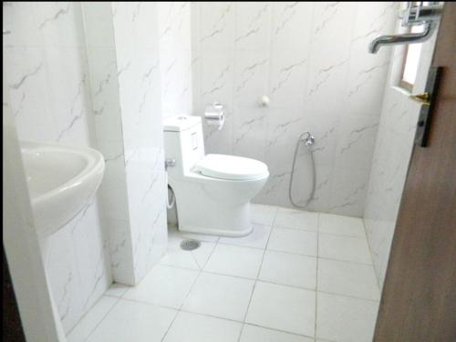a white bathroom with a toilet and a sink at Mount Annapurna Guest House in Kathmandu