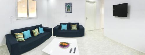 a living room with two blue couches and a table at Dwiret Hayet Kélibia in Kelibia