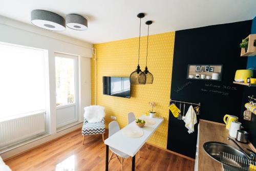 a kitchen with a white table and a yellow wall at Smile apARTment in Novi Sad