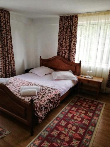 a bedroom with a large bed and a rug at Pensiunea Broscuta in Horezu