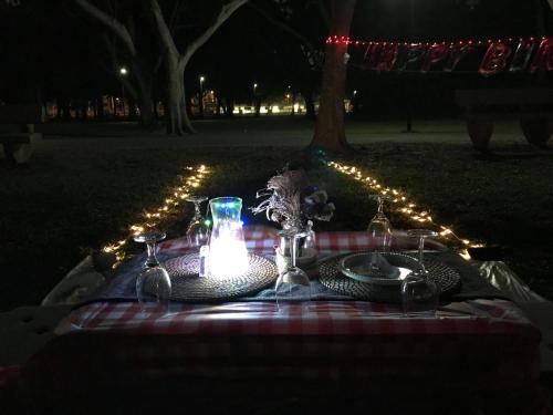 Glamping Kaki - Medium Bell Tent في سنغافورة: طاولة نزهة بها شمعة وأطباق وأضواء