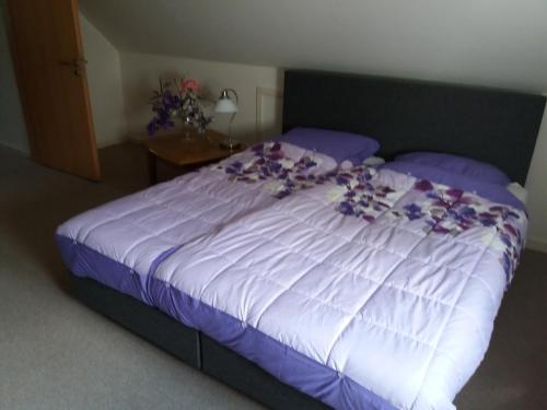 a bed with purple flowers on it in a bedroom at Casa Martin in Porumbacu de Sus