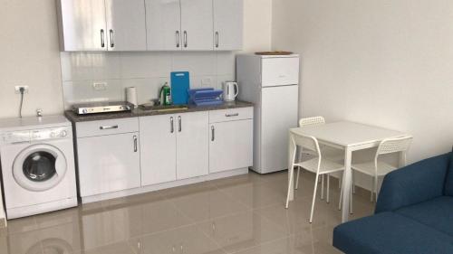 a kitchen with a washer and a table and a refrigerator at Isramax apartment near the beach. in Bat Yam