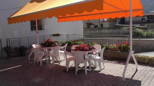 a table and chairs under an umbrella on a patio at Hotel Galles in Paluzza
