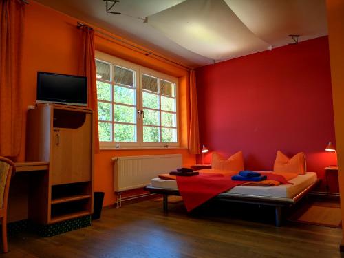a bedroom with red walls and a bed with orange pillows at Golfcentrum Schloss Karnitz Rügen in Garz-Rügen
