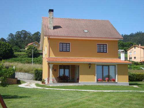 a small yellow house with a grass yard at Casas Cuncheiro in Canduas