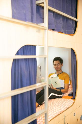 a man sitting on a bunk bed with a laptop at Rocket Hostels Gracia in Barcelona