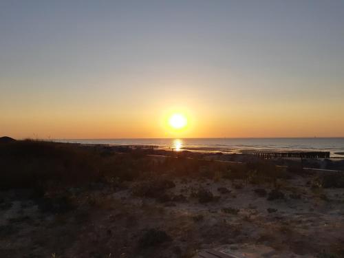 a sunset over the ocean with a pier at le vergoyer in Calais