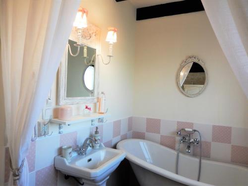 W łazience znajduje się umywalka, wanna i lustro. w obiekcie La Cordonnerie de Réau w mieście Réau