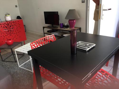 une salle à manger avec une table noire et une chaise rouge dans l'établissement Le Petit Lecoy, à Saumur