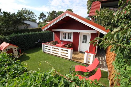 ein rotes Haus mit roten Stühlen im Hof in der Unterkunft Blockbohlenhaus Plau am See in Plau am See