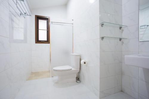 a white bathroom with a toilet and a sink at Arantarakiri Resort Khao Yai in Mu Si