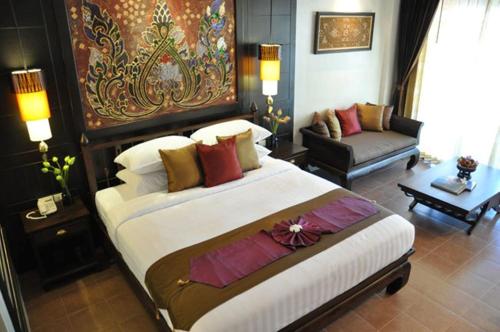a bedroom with a large bed and a couch at Siralanna Hotel in Patong Beach