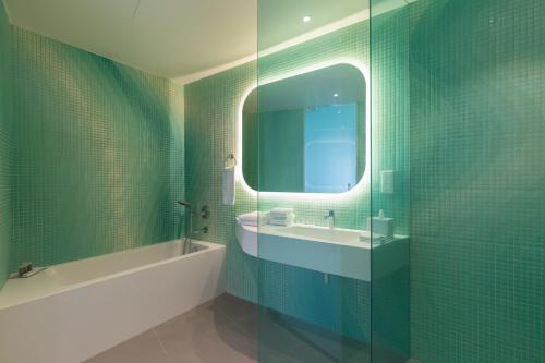 a bathroom with a tub and a sink and a mirror at Park Inn by Radisson Amsterdam City West in Amsterdam