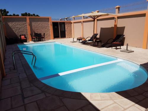 a large blue swimming pool with chairs and an umbrella at Select Hôtel in Morondava