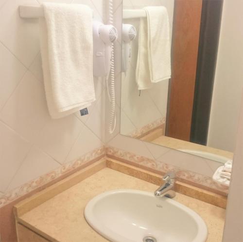 a bathroom with a sink and a mirror and towels at Apartamentos Mendoza in Mendoza