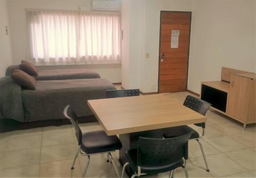 a room with a bed and a table and chairs at Premium Mendoza Apart Hotel in Mendoza
