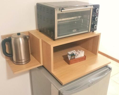 a microwave and a toaster oven on a wooden shelf at Premium Mendoza Apart Hotel in Mendoza