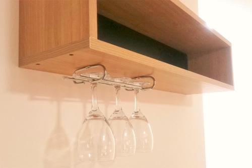 four glass wine glasses hanging from a cabinet at Premium Mendoza Apart Hotel in Mendoza