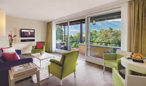 a living room with a couch and chairs and a large window at Giardino Ascona in Ascona
