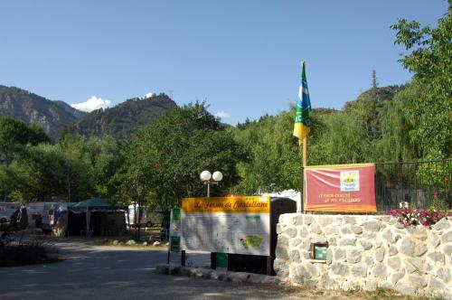 a flag on top of a stone wall with a sign at Camping La Ferme de Castellane in Castellane