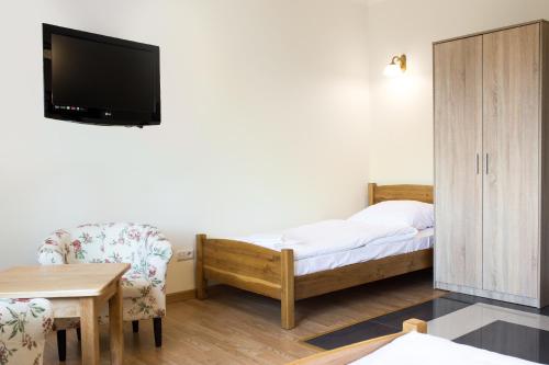 a bedroom with a bed and a tv and a chair at Dworek Zyskowskiego in Danowskie