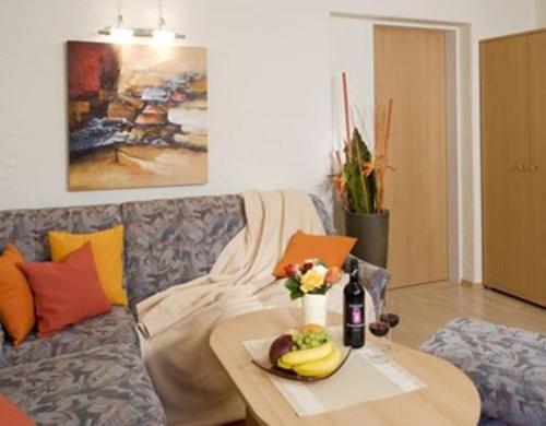 a table with a plate of fruit and a bottle of wine on a couch at Apartment Landhaus Krall in Westendorf