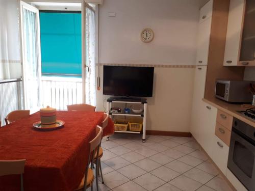 een woonkamer met een tafel en een keuken met een televisie bij appartamento vicino al mare Alassio in Alassio
