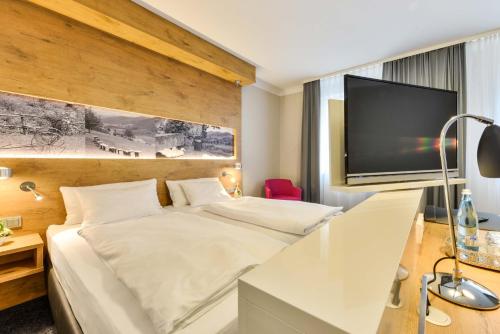 a hotel room with a bed and a flat screen tv at Hotel Restaurant Sonne in Gengenbach