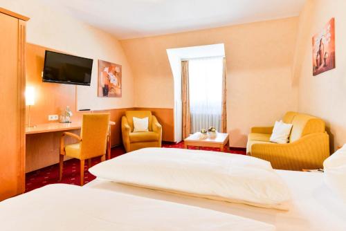a hotel room with a bed and chairs and a tv at Hotel Restaurant Sonne in Gengenbach