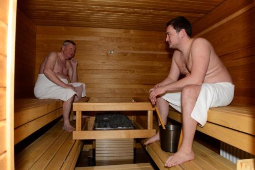 two men are sitting in a sauna at Hotelli Salpa in Luumäki