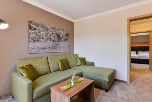 a living room with a green couch and a table at Hotel Restaurant Sonne in Gengenbach