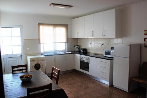 eine Küche mit weißen Schränken und einem Tisch mit einer Schale Obst in der Unterkunft Vila Mar in Vila Franca do Campo