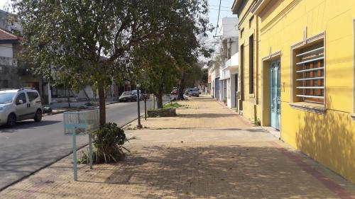 a street with a yellow building and a tree at La Glicina casa in La Plata