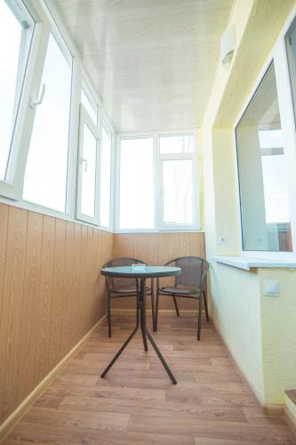 una mesa y una silla en una habitación con ventanas en Vip apartmen Harkovskaya, en Sumy